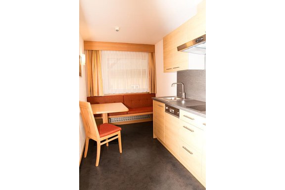 A modern kitchenette with wooden cabinets and a small dining area. The cozy seating corner invites you to linger. - Hotel Garni Ehrenreich - Sölden