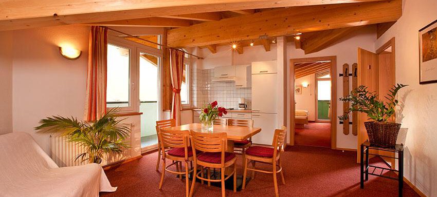 A bright apartment with wooden ceilings and a dining area. The decor is cozy and inviting, with plants and windows that let in plenty of light. - Hotel Garni Ehrenreich - Sölden