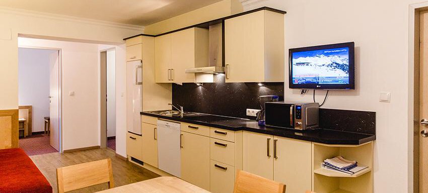 A modern kitchen corner with bright cabinets and a dining area. The space is well lit and offers a cozy atmosphere. - Hotel Garni Ehrenreich - Sölden