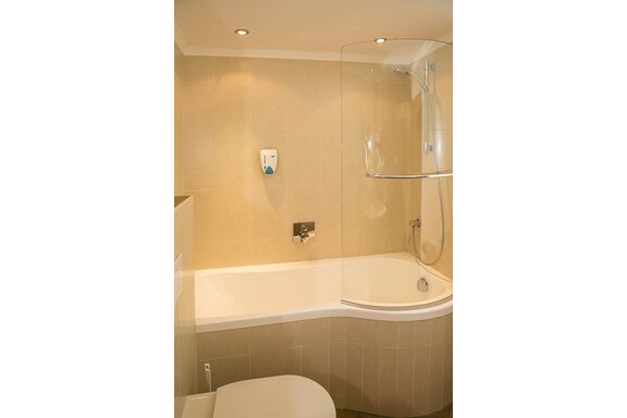A modern bathroom with a shower and a bathtub. The walls are painted in soft, light colors. - Hotel Garni Ehrenreich - Sölden