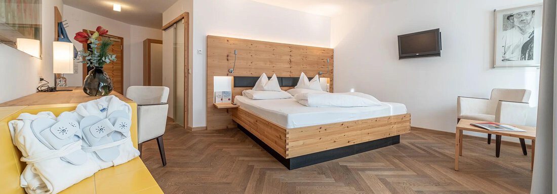 Hotel Liebe Sonne Junior Suite Brunnenkogl | © Hotel Liebe Sonne (CC C) A modern bedroom with a large bed and wooden furniture. The cozy atmosphere is emphasized by the warm colors and soft light. - Hotel Liebe Sonne - Sölden