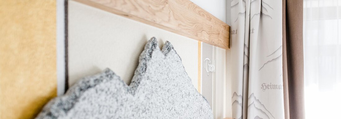 A modern room with a wooden headboard and an artistic mountain elevation. The curtains create a bright and inviting atmosphere. - Hotel Sportpension Carinthia - Sölden