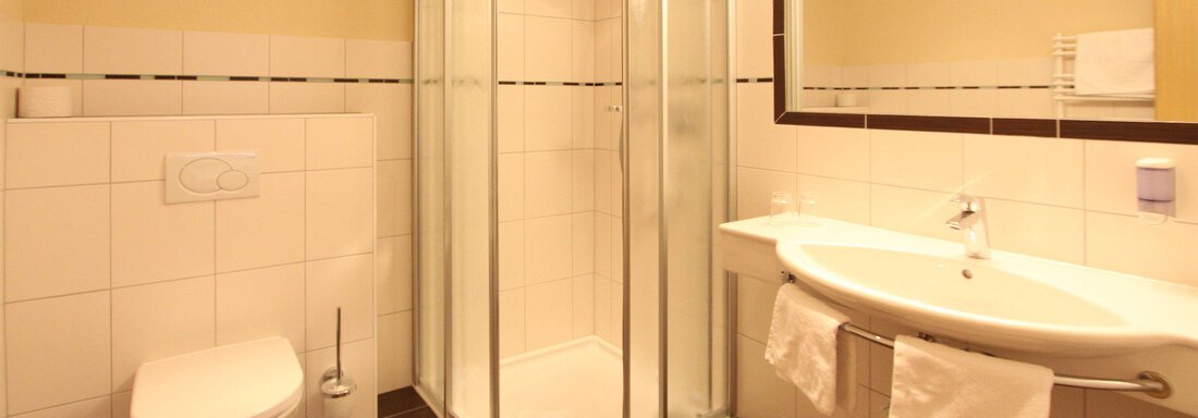 App1_Badezimmer A modern bathroom with a glass shower and a sink. The walls are brightly tiled, and there is a large mirror surface. - Hotelappart Peter - Sölden