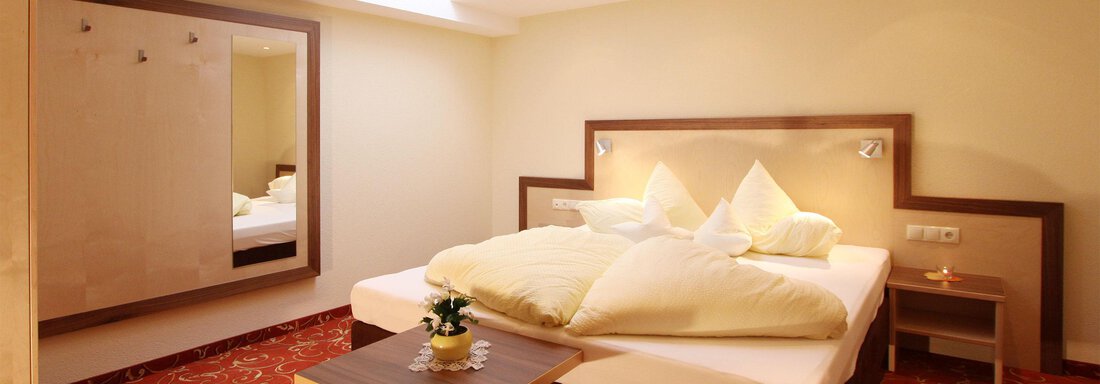 A modern bedroom with a large bed and fresh pillows. The warm tones create an inviting atmosphere. - Hotelappart Peter - Sölden