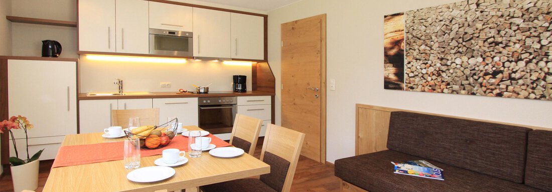 Wohnküche mit Essbereich | © Georg Falkner A modern kitchen and dining room with bright furniture. The table is lovingly set and a cozy seating area invites you to relax. - Hotelappart Peter - Sölden