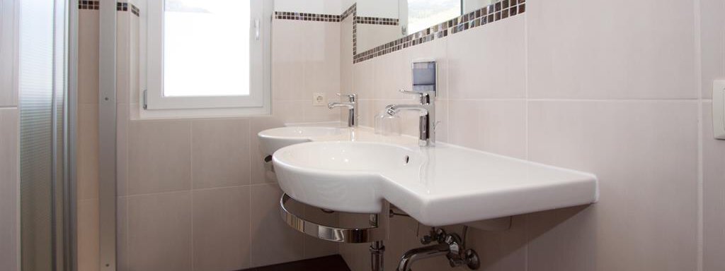 A modern bathroom with two sinks and a large shower. Bright walls and an elegant floor create an inviting atmosphere. - Hotelappart Peter - Sölden