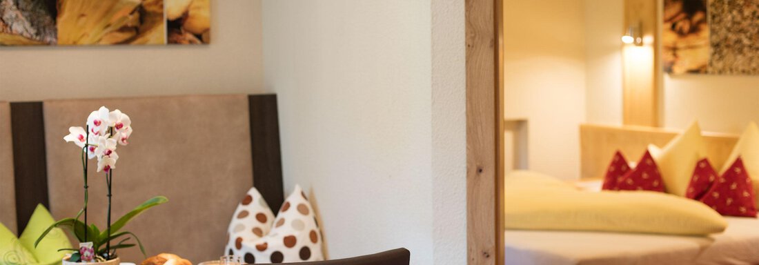 App 4 Essplatz mit Blick ins Zimemr | © Falkner Georg A cozy room with a dining table, decorated cushions, and a bedroom in the background. The atmosphere is inviting and modern. - Hotelappart Peter - Sölden