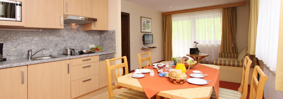 Wohnküche Appt. 11 A modern kitchen with a dining area. The table is set with dishes and a breakfast buffet. - Hotelappart Peter - Sölden