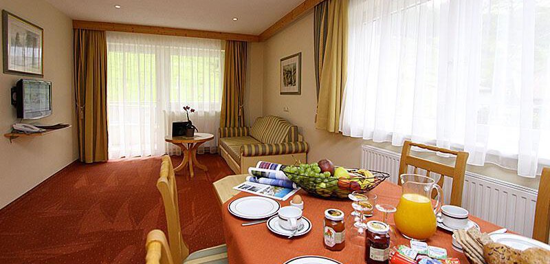 A cozy breakfast room with a table set with food and drinks. Bright windows and pleasant decor create an inviting atmosphere. - Hotelappart Peter - Sölden