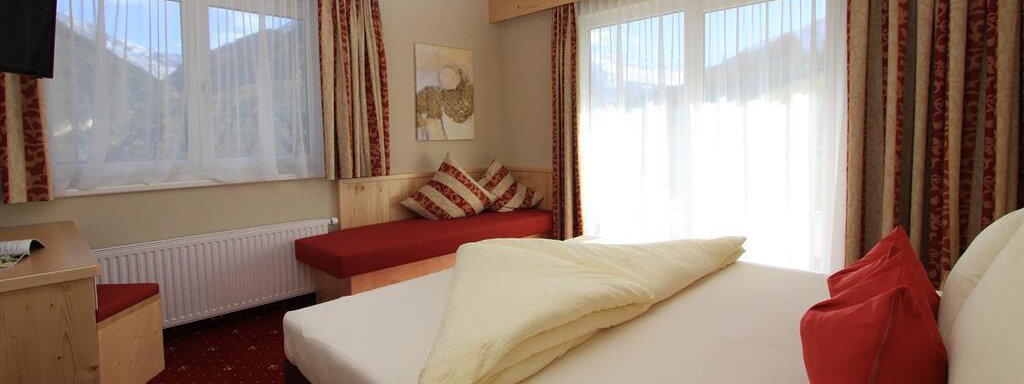A cozy bedroom with a large bed and soft colors. The room has large windows that provide a lot of light and a relaxed atmosphere. - Hotelappart Peter - Sölden