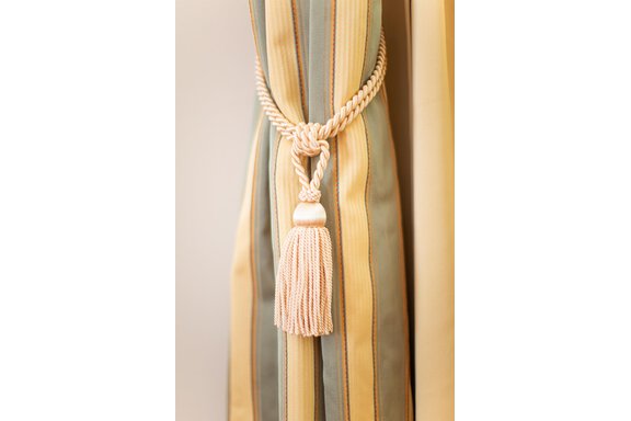 A decorative curtain with a striped pattern and an elegant cord with a tassel. The colors are soft and harmonious. - Hotelappart Peter - Sölden
