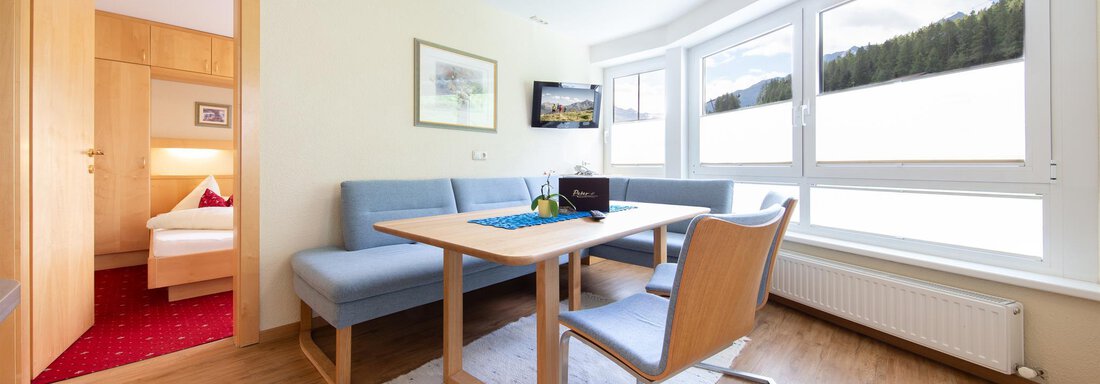 4 A bright and modern room with a table and chairs. Large windows offer a view of nature outside. - Hotelappart Peter - Sölden