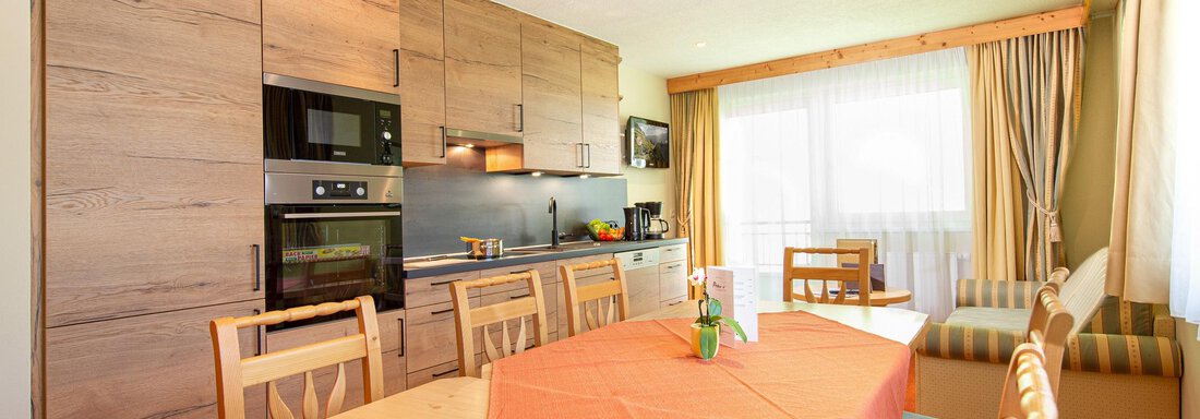 A modern kitchen with a wooden dining area. Large windows let in plenty of light and create an inviting atmosphere. - Hotelappart Peter - Sölden