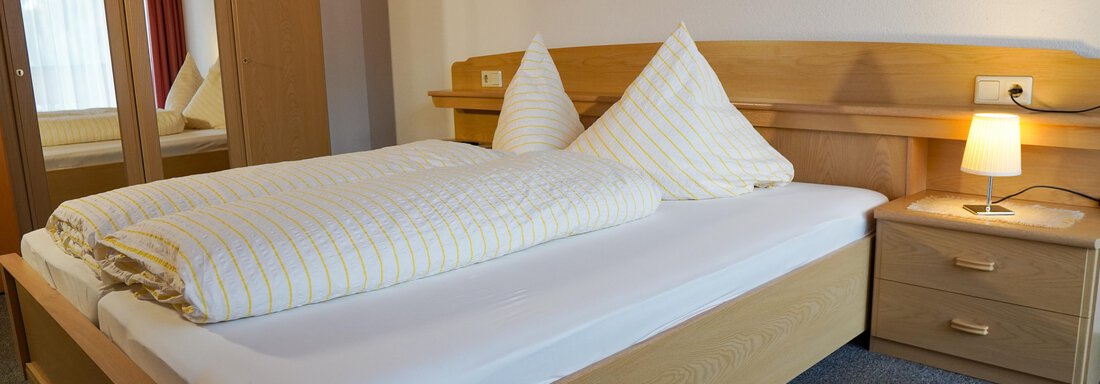 Ein gemütliches Schlafzimmer mit einem Doppelbett und zwei Kopfkissen. Neben dem Bett befindet sich ein Nachttisch mit einer Lampe. - La Luna - Sölden