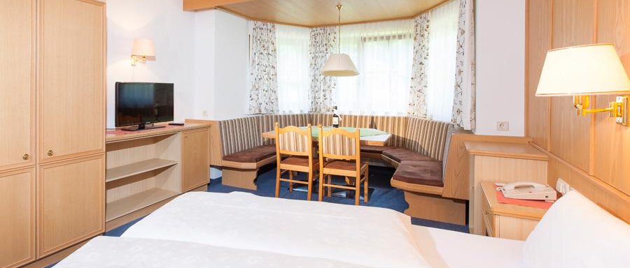 Wohnraum mit Schlafcouch A cozy hotel room with a double bed and a dining area. Bright furniture and plenty of daylight create an inviting atmosphere. - Landhaus Falkner - Sölden