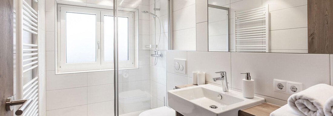 A modern bathroom with a glass shower and a sink. Bright walls and soft lighting create an inviting atmosphere. - Landhaus Falkner - Sölden