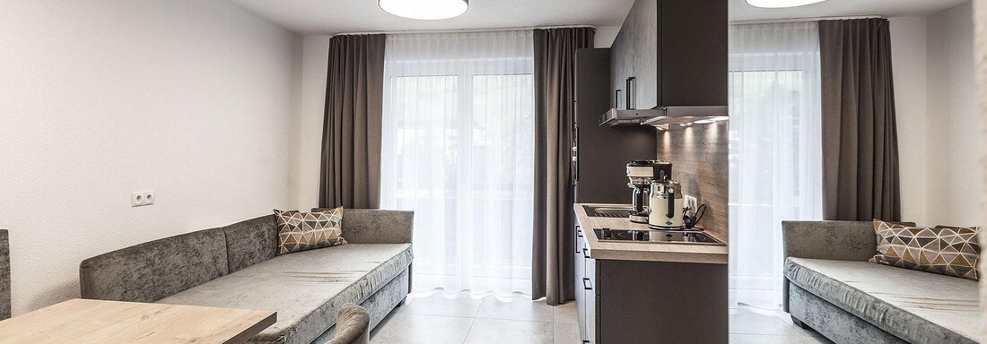 A modern kitchen with a cozy dining area. Large windows with curtains provide plenty of light. - Landhaus Falkner - Sölden