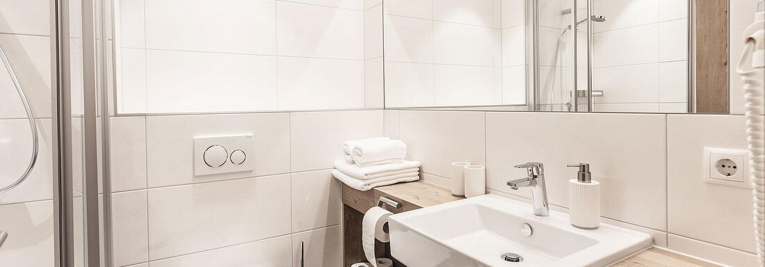 A modern bathroom with bright tiles and elegant fixtures. The wash area is clean and designed in a minimalist style. - Landhaus Falkner - Sölden