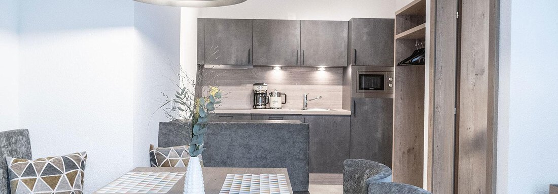 A modern kitchen with a dining area. The room is designed to be bright and functional. - Landhaus Falkner - Sölden