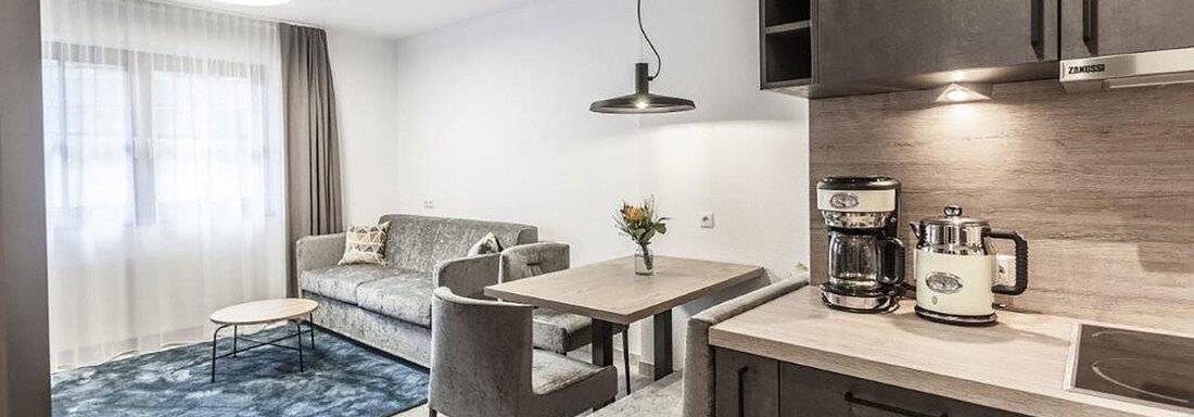 Wohnküche A modern living kitchen with a comfortable sofa and a dining table. The bright atmosphere is enhanced by large windows and a stylish interior design. - Landhaus Falkner - Sölden