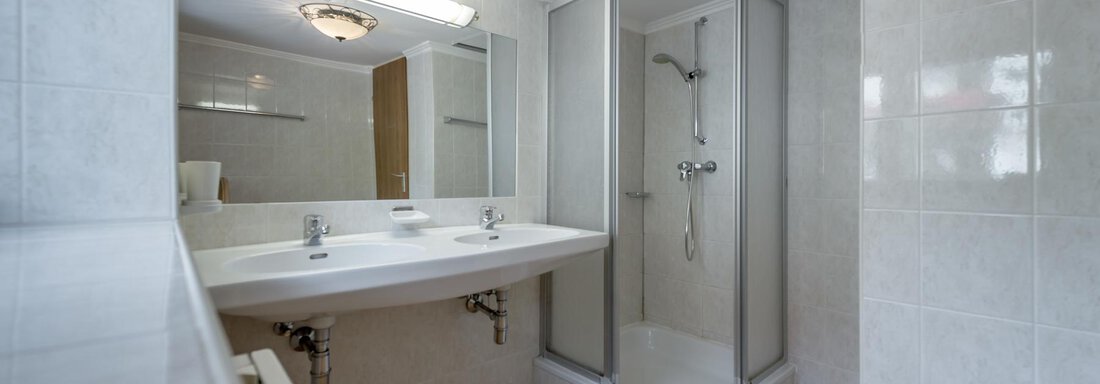 A modern bathroom with a shower and double sink. The walls are brightly tiled and the space feels inviting and clean. - Landhaus Peater's Hoamat - Sölden