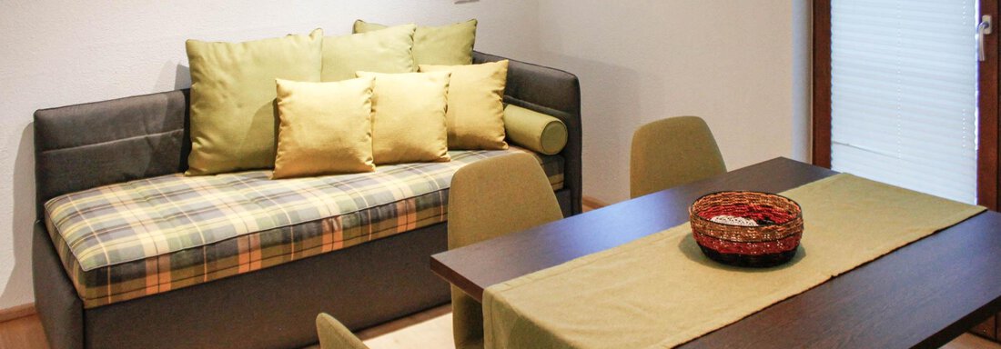 A cozy living room with a sofa and a dining set. A decorative bowl is on the table. - Lutonia Appartements Sölden - Sölden