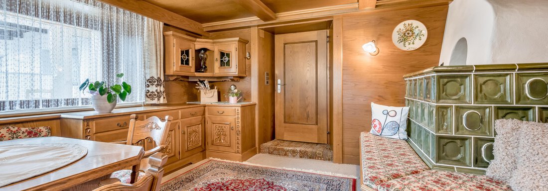 A cozy living space with wood paneling and traditional decor. The area is bright and inviting, with a dining table and a seating area. - Lyns Home - Sölden