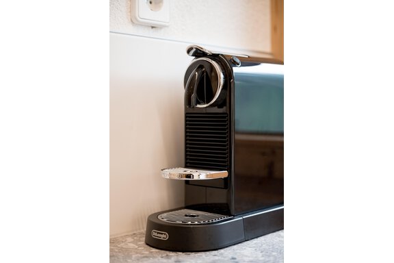 An elegant black coffee machine is on a countertop. It has a modern design and is ready for brewing coffee. - Lyns Home - Sölden