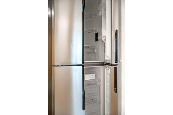 A modern stainless steel refrigerator with an open door. The interior is clean and empty, ready for groceries. - Lyns Home - Sölden