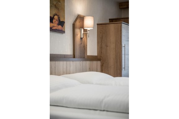 A cozy bedroom with a large bed and modern wooden interior.  
On the wall hangs a piece of artwork, and there is a floor lamp that provides pleasant lighting. - Lyns Home - Sölden
