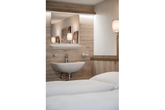 A modern room with two beds and an elegant sink. The walls are made of light wood and there is soft lighting. - Lyns Home - Sölden