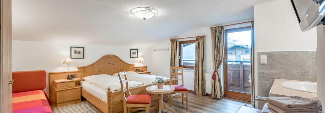 A cozy room with a double bed and a single bed. There is a table with chairs and a balcony overlooking the outside. - Lyns Home - Sölden
