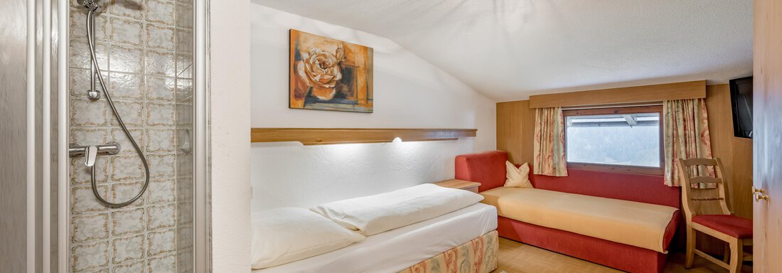 A cozy room with a double bed and a sofa. There is a bathroom with a shower and a window overlooking the outside. - Lyns Home - Sölden