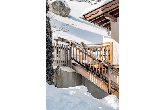 A cozy wooden terrace with a small staircase, surrounded by snow-covered landscapes. Snowy mountains are visible in the background. - Lyns Home - Sölden