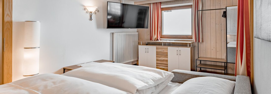 A modern room with a double bed and comfortable furnishings. It features a television and space for luggage. - Lyns Home - Sölden