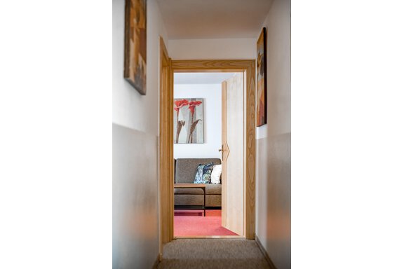 A bright hallway leading to a living room. In the background, you can see a sofa and decorative pictures on the walls. - Lyns Home - Sölden