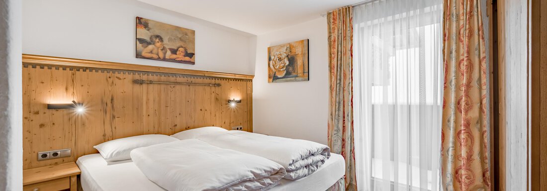 A cozy bedroom with a large bed and wood paneling.  
Plenty of light through the windows and an inviting atmosphere. - Lyns Home - Sölden