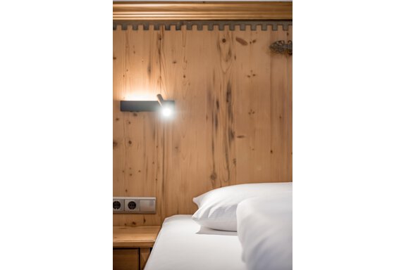 A cozy bedroom with bright cushions and wood paneling. A modern lamp provides soft light. - Lyns Home - Sölden