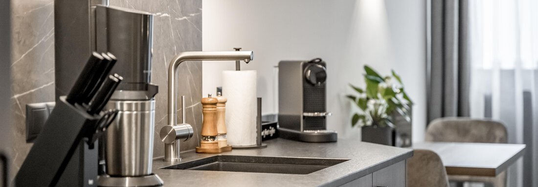 A modern kitchen with an elegant kitchen workspace. On the counter, various kitchen utensils and a coffee machine can be seen. - Marco's Mountain Home - Sölden