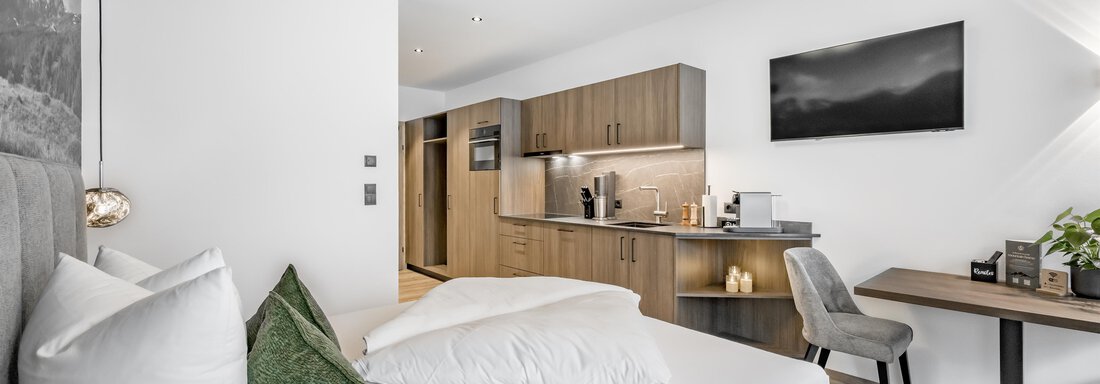A modern room with a comfortable bed and a cozy seating area. The kitchen is well-equipped and there is a bright, inviting atmosphere. - Marco's Mountain Home - Sölden