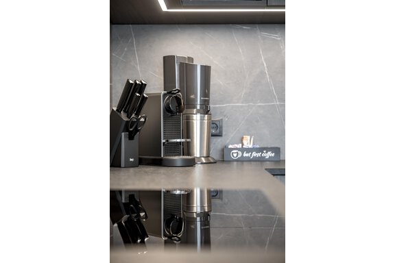 A modern kitchen with a coffee machine and a set of kitchen knives. On the countertop, there is a box with the inscription "but first coffee". - Marco's Mountain Home - Sölden
