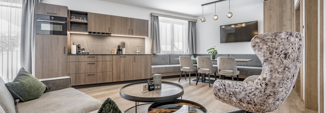 Apartment vier'ar oder sechs'ar A modern living room with an elegant kitchenette and comfortable furniture. There is a large table with chairs and stylish lighting. - Marco's Mountain Home - Sölden