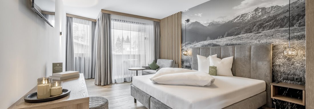 A modern bedroom with a large bed and a beautiful view of the mountains. The decor is minimalist and bright, with large windows and a cozy atmosphere. - Marco's Mountain Home - Sölden