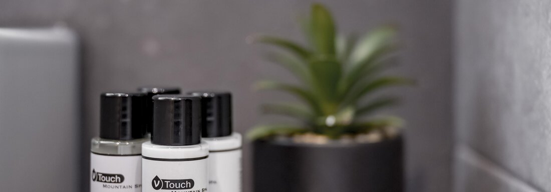 A stylish bathroom with care products in bottles and a small plant in the background. The atmosphere is modern and relaxing. - Marco's Mountain Home - Sölden