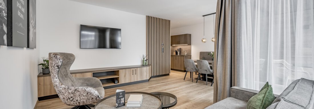 A modern living room with a cozy lounge area, a television, and elegant lighting. The large windows let in plenty of light and create a pleasant atmosphere. - Marco's Mountain Home - Sölden