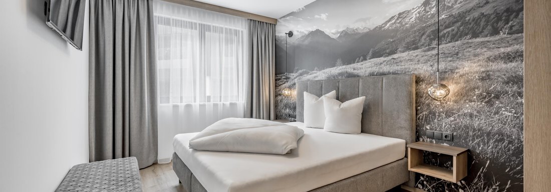 A modern bedroom with a large bed and soft colors. The wall behind the bed features a landscape painting with mountains. - Marco's Mountain Home - Sölden