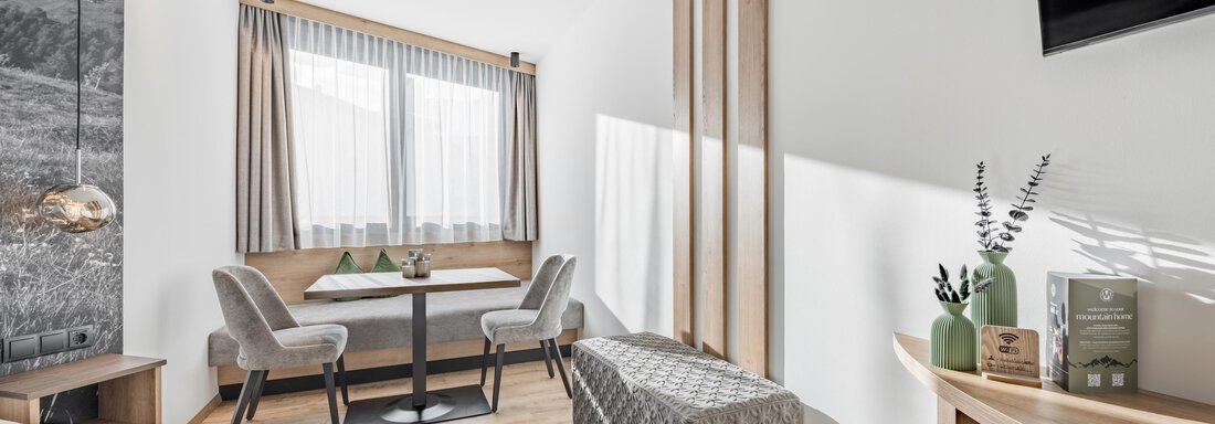 A modern room with wood details, a table, and cozy chairs. Bright windows create a friendly atmosphere. - Marco's Mountain Home - Sölden