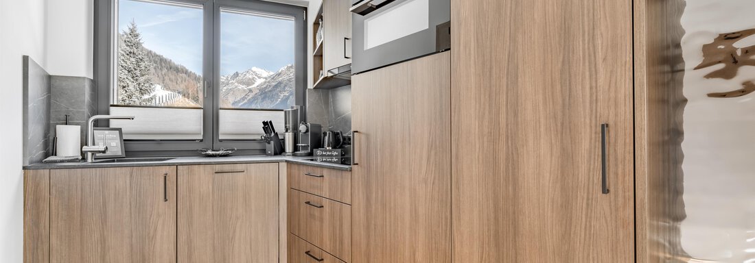A modern kitchen with wooden cabinets and appliances. The window offers a view of the mountains. - Marco's Mountain Home - Sölden