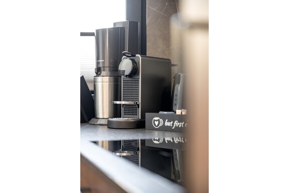 A modern coffee kitchen with an elegant coffee machine and a stylish thermos. On the countertop, there is a sign that reads "but first coffee". - Marco's Mountain Home - Sölden