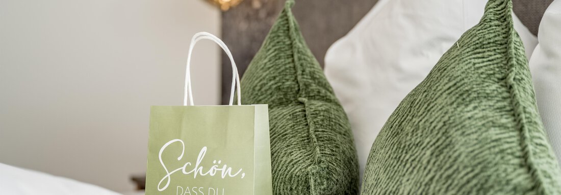 A cozy bedroom with two green pillows and a gift bag. The bag has the inscription "Nice to have you here." - Marco's Mountain Home - Sölden